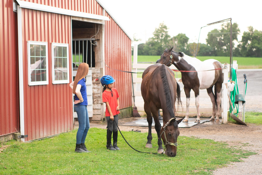 Karen Favata watches closely as lesson students care for their horses